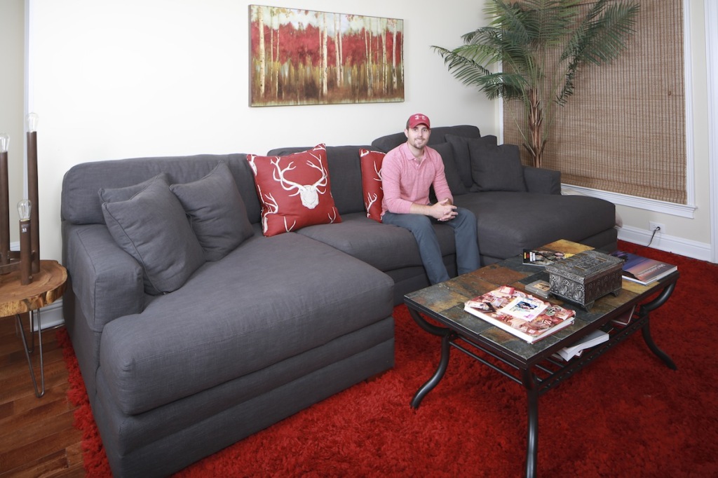 Matt Busbice in his living room, which prominently features his current favorite color, red. The oversized sofa is ideal for hanging out with friends when Matt’s not working or on the set of his Outdoor Channel show.