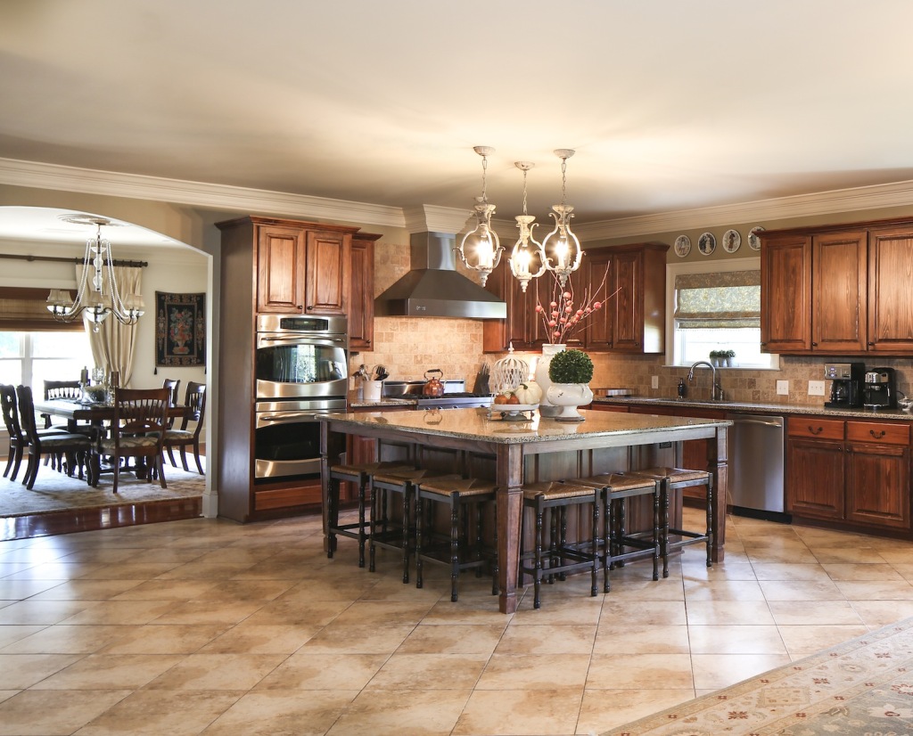 With its warm stained cypress cabinets and neutral granite countertops and tile flooring, the spacious kitchen is an inviting place for cooking big family meals. 