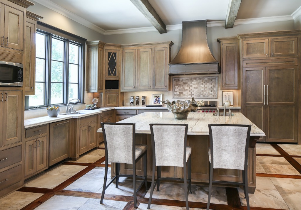 The finishes in the kitchen are refined but can withstand rugged wear. Faux python-skin upholstered barstools “have a lot of character, but they’re pretty indestructible,” says Jerad. The solid quartz slab countertop requires little special care, and the porcelain slate tile floor is tougher than the real thing. Stained maple cabinets play well with a basketweave-patterned marble backsplash and a range hood finished by artist Connie Perque to look like zinc.