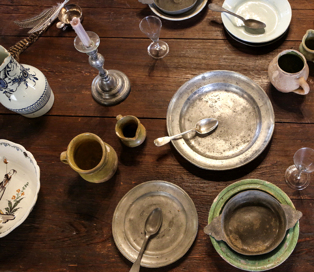 An assortment of pitchers, bowls and other artifacts unearthed during archaeological excavations in Louisiana is displayed on a trestle table in the LaCour House’s smaller room.
