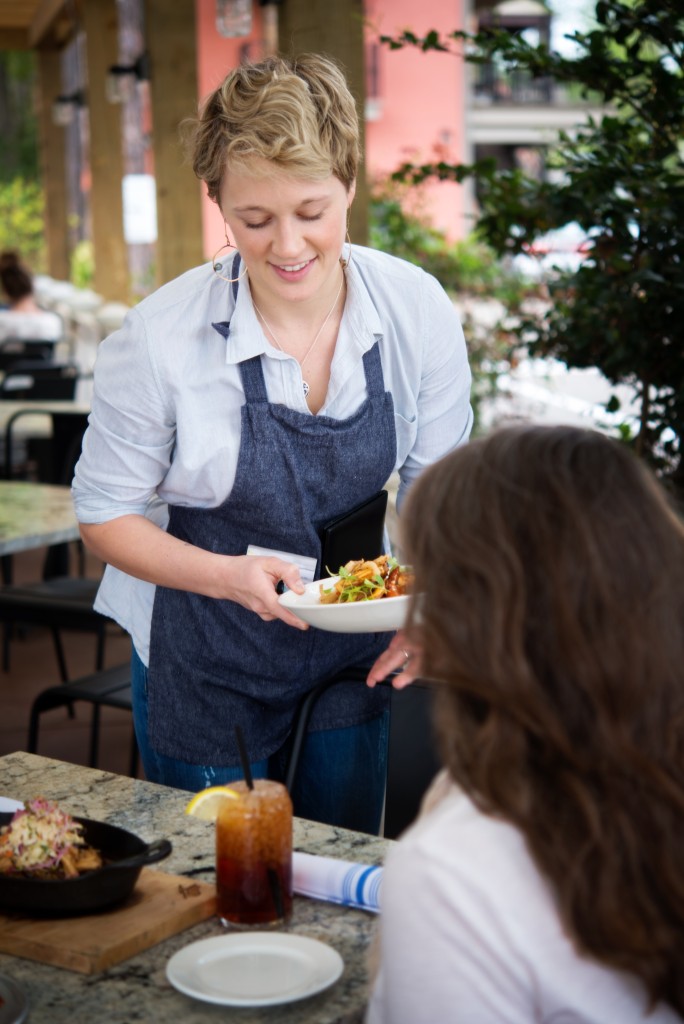 A server at City Pork brings out dishes to the restaurant's patio.
