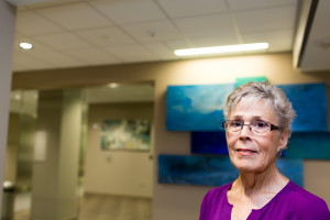 Nora Taylor, two-time cancer survivor, stands in front of Robert Rector’s “Waters of the World.” The artwork in the facility is meant to be directional, guiding patients from one corridor to the next.